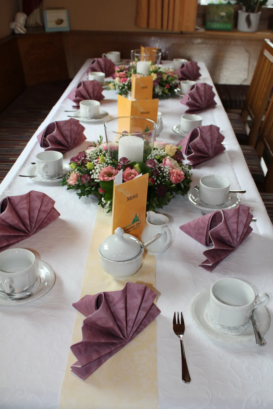 Festlich gedeckte Tafel mit Blumenschmuck in der Gaststube des Kolmsteiner Hofs